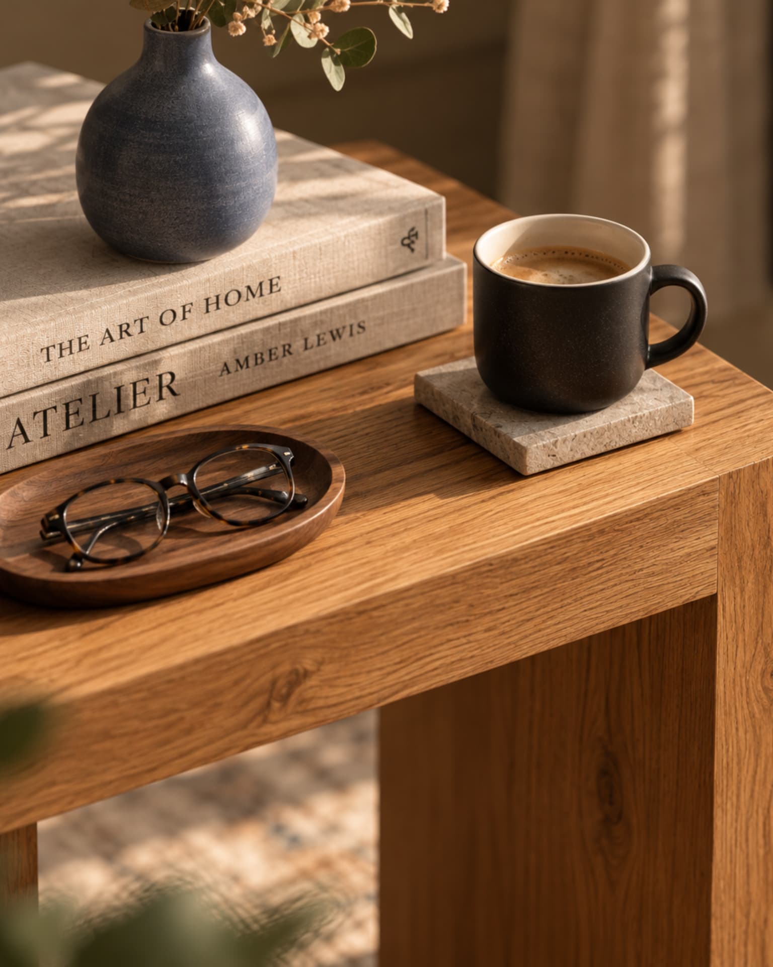 Detail of books, coffee and eyewear on an oak side table